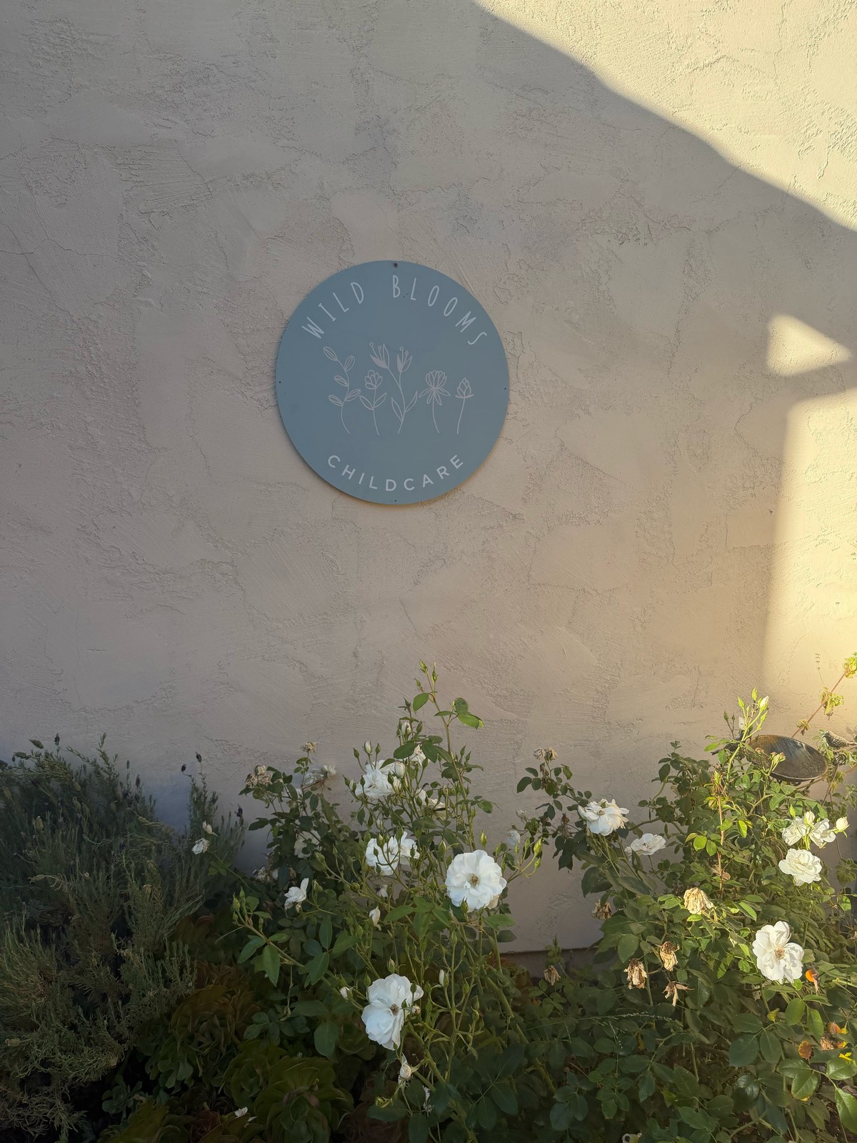 Wild Blooms Childcare sign with white roses